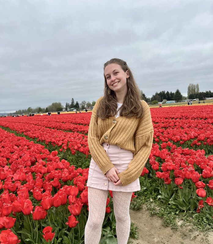 Elise Tahti smiling in front of rows of red tulips