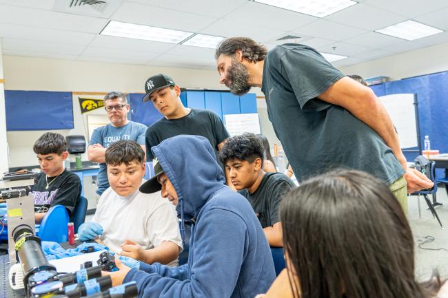 Western Assistant Professor of Biology Nick Galati stands behind a group of Mount Vernon High School students as they work on building a microscope.